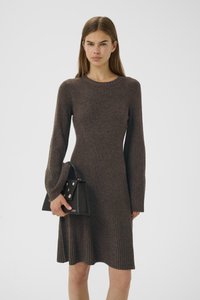 Ribbed ruskea mekko pitkillä hihoilla ja pyöreällä kaula-aukolla, yhdistettynä mustaan laukkuun, jossa on hopeiset yksityiskohdat ja strukturoidun muotoilu.