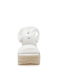 Sandalo bianco con pianta alta, con cinturini superiori intrecciati, suola in iuta stile espadrille, superficie liscia, forma affusolata e punta chiusa.