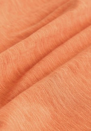 Ľahká, textúrovaná látka v jemnej koralovej farbe, s diskrétnymi tkanými vzormi a jemným padaním, ideálna na odevy.