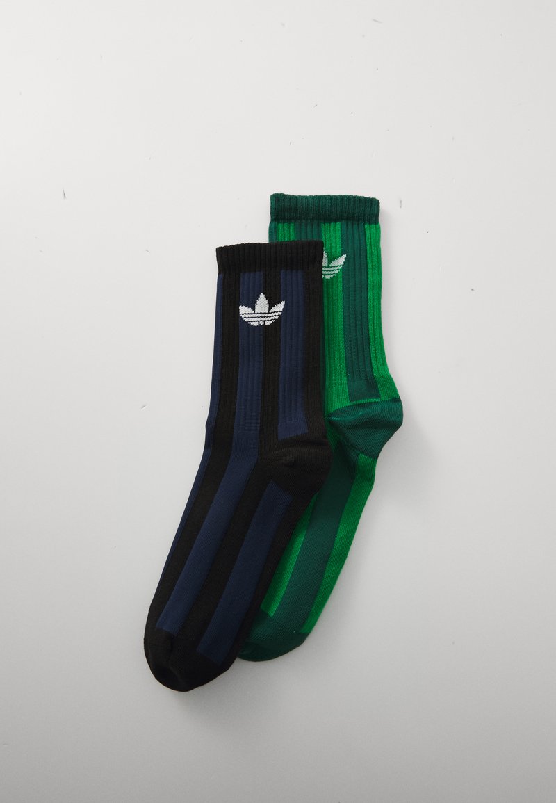 Dos pares de calcetas acanaladas, uno en azul oscuro y negro, el otro en verde, cada uno con un logotipo blanco de Adidas.