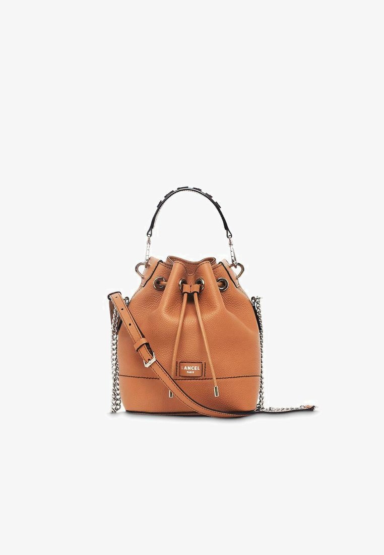 Sac seau en cuir tan avec fermeture à cordon, une chaîne en bandoulière et une poignée supérieure. Présente un branding embossé et une surface texturée.