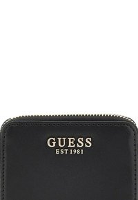 Portafoglio in pelle nera con zip dorata e logo impresso "GUESS EST 1981" sulla parte anteriore, caratterizzato da una texture liscia e una forma rettangolare elegante.