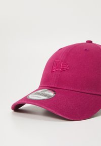 Rózsaszín baseball sapka ívelt karimával, textúrázott anyaggal és hímzett logóval az elején. Állítható méretű, címkés.