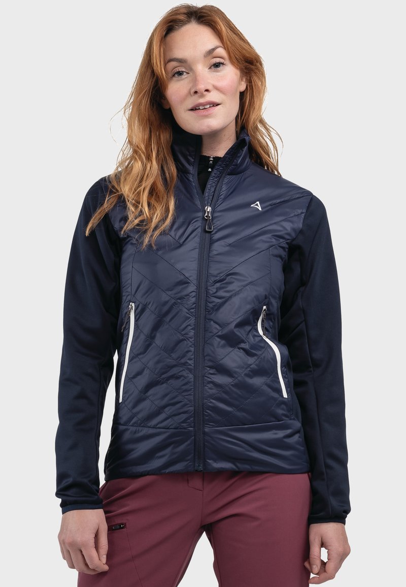 Marineblaue isolierte Jacke mit gesteppter Vorderseite, Reißverschlusstaschen und kontrastierenden weichen Ärmeln. Sie verfügt über einen hohen Kragen und ein schlankes, modernes Design.