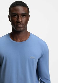 Light blue long-sleeve shirt made of soft fabric, featuring a crew neck and embroidered "BOSS" logo on the left chest.
