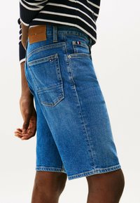 Spijkerbroek shorts in een middelblauwe wassing, met een leren label aan de achterkant, rechte pasvorm en vijf zakken met subtiele rode en witte accenten.