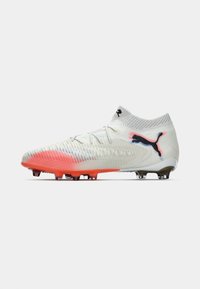 Witte voetbalschoenen met oranje accenten, zwart Puma-logo en een sokachtige enkelkraag, zijwaarts weergegeven op een witte achtergrond.