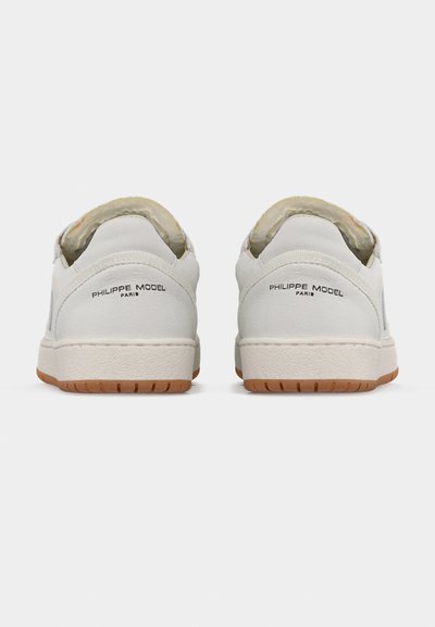 Baskets en cuir blanc avec une finition texturée, semelle en caoutchouc beige et doubles languettes arrière. Logo noir imprimé sur le talon et la languette.