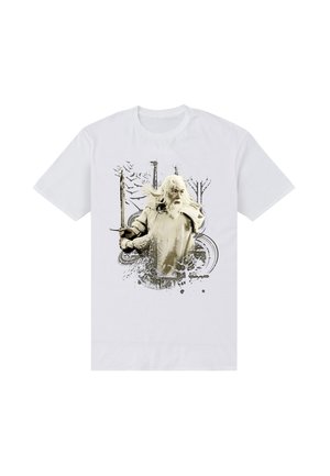 T-shirt blanc représentant un homme âgé aux longs cheveux blancs et à la barbe tenant une épée, avec des arbres abstraits et des oiseaux volant en arrière-plan.