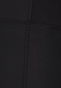 Mustat urheiluleggingsit, joissa on sileä pinta, litteät saumat ja istuva malli. Ei näkyviä kuvioita tai kiinnikkeitä.