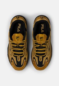 Scarpe athletic gialle e nere con design testurizzato, realizzate in materiali scamosciati e in rete, con lacci spessi e un logo prominente sulla linguetta.