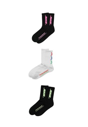 Tres pares de calcetines para tripulación: negros con texto rosa, blancos con chevrones rojos, azules y verdes y texto, y negros con texto amarillo pálido, extendidos planos.