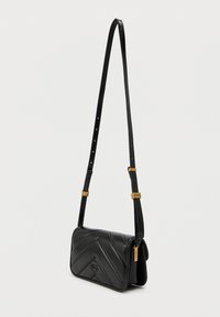 Μαύρη δερμάτινη τσάντα χιαστί με ραφή ζιγκ-ζαγκ, ρυθμιζόμενο λουρί και λεπτομέρειες σε χρυσό τόνο.