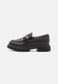 Sorte læder loafers med en bred, struktureret overdel, guldfarvet hardwareaccent og en kraftig gummisål med dybe riller for godt greb.