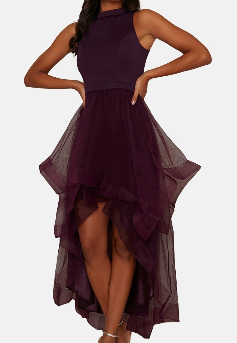 Burgundy mekko, jossa on istuva yläosa ja korkea-matalat tyllihameet. Hameessa on kerroksellisia volaanteja ja pehmeä, läpikuultava textura.