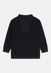 Maglione a maglia scura con colletto alto e zip sul retro. Tessuto a costine, maniche lunghe e vestibilità rilassata. Nessun motivo o accento visibile.