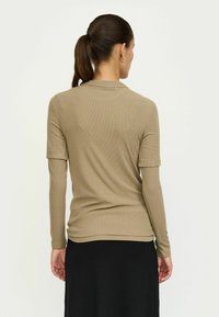 Taupe ribbet jersey top med korte ærmer, tætsiddende design og rund halsudskæring, parret med en sort nederdel, vist fra ryggen.