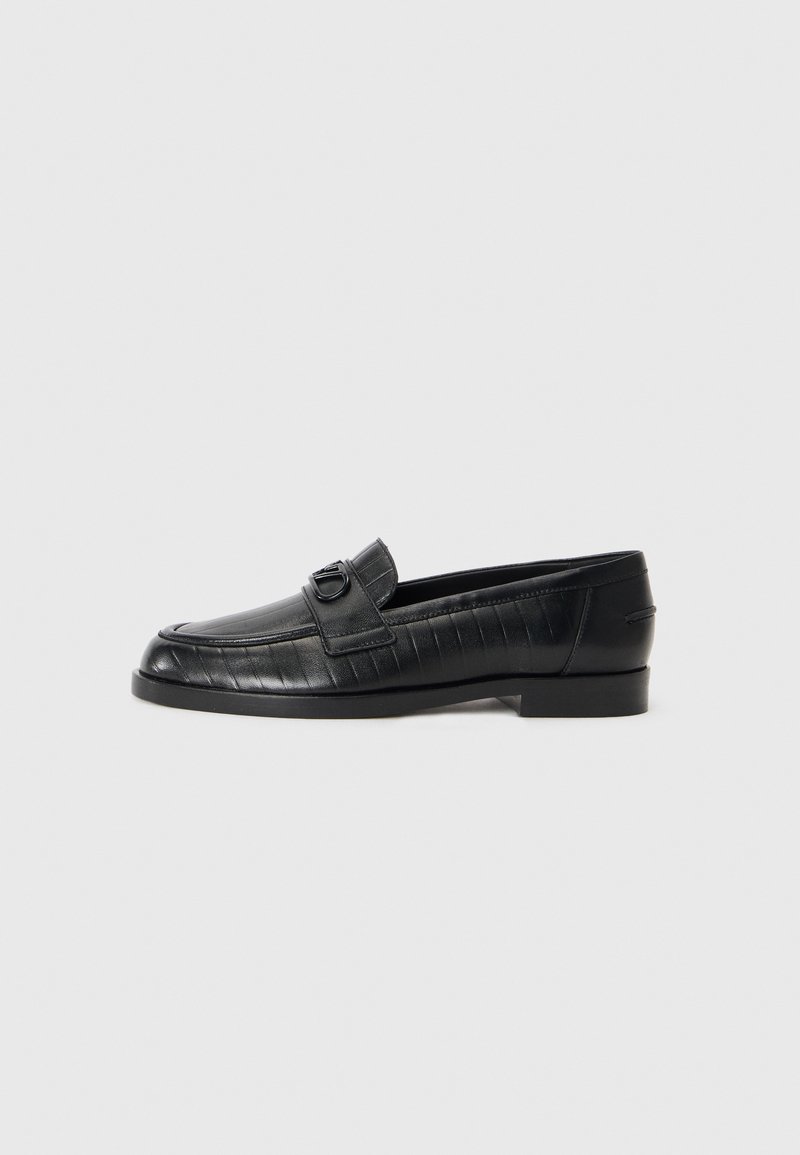 Black leather loafers with a smooth upper, embossed linear pattern, and a decorative buckle accent on the vamp. Low, block heel.