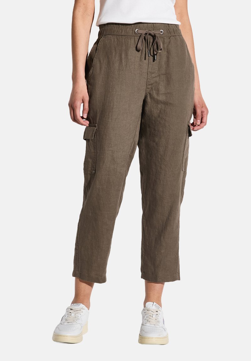 Cargo-byxor i olivgrön linne, med dragsko i midjan, avsmalnande ben och sidofickor. Bärs tillsammans med vita sneakers.