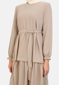 Beige långärmad klänning med knytbart bälte i midjan, med en lager-på-lager, lös passform och rynkade ärmar för extra textur.