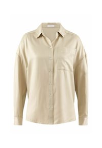 Chemise beige à manches longues en tissu lisse, avec un col et une poche sur le côté gauche.