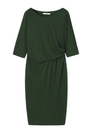 Tume roheline põlveni ulatuv kleit kolmeveerand varrukatega ja vöökoha kokkutõmmatud detailiga ühtlasel taustal.