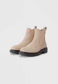 Stivaletti beige in suede con pannelli elastici laterali e linguetta, dotati di una spessa suola in gomma nera con battistrada testurizzato.