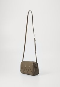 Borsa a tracolla sintetica marrone di forma rettangolare, con un design a zigzag sul davanti e una cintura sottile regolabile. Cerniera argento.