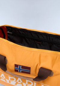 Borsa in tela gialla con un interno nero, manici in tessuto marrone e una patch decorativa con la bandiera norvegese. Presenta un'apertura con zip.