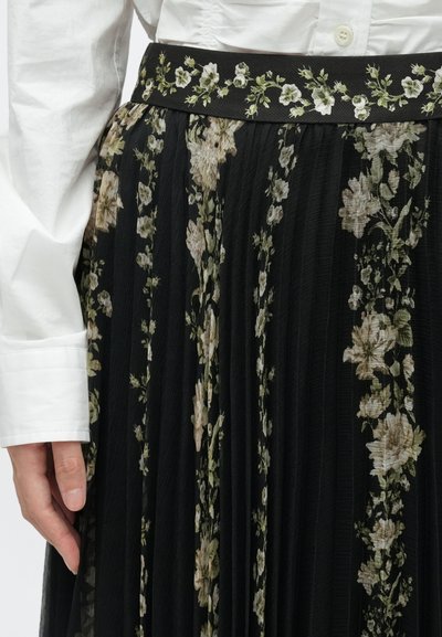 Crna plisirana suknja s cvjetnim uzorkom u krem i zelenoj boji. Ima čvrst crni pojas s izveznim cvjetnim detaljima.