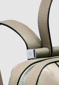 Sac en cuir beige avec bordure noire contrastante, comprenant deux sangles robustes et un fermoir en métal argenté, mis en valeur par une texture lisse et des coutures soignées.