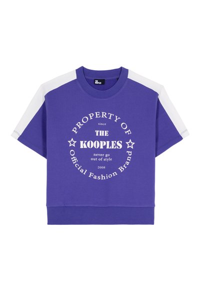 Fioletowa koszulka z krótkim rękawem z białymi paskami na ramionach i okrągłym białym napisem "Własność Marki Mody KOOPLES" z przodu.