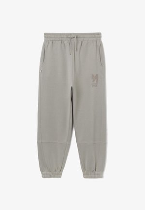 Pantalones de chándal grises hechos de tela suave, con una cintura elástica, bolsillos laterales y un logotipo bordado en el muslo izquierdo.