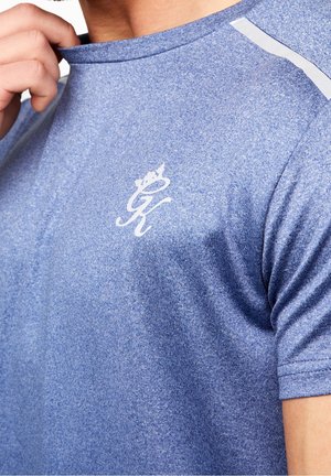 Blaues Sport-T-Shirt mit einem strukturierten Muster, das ein weißes Logo auf der Brust und weiße Akzente an den Schultern aufweist. Kurze Ärmel.