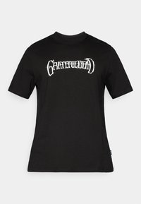 Μαύρο βαμβακερό μπλουζάκι με λευκό γραφικό τύπωμα της επιγραφής «GRATEFUL DEAD» σε στιλιζαρισμένη γραμματοσειρά στο στήθος. Κοντά μανίκια και στρογγυλή λαιμόκοψη.