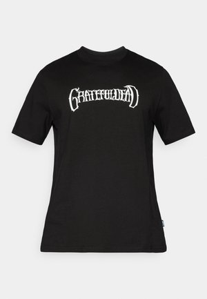 Zwart katoenen T-shirt met een witte grafische opdruk van "GRATEFUL DEAD" in een gestileerd lettertype over de borst. Korte mouwen en een ronde hals.