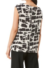 Ærmeløs top i creme med et sort abstrakt blokmønster, blødt stof, rund udskæring bagpå og en lige kant.