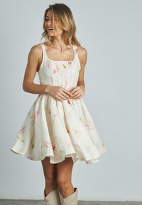 Vestido con estampado floral, de escote cuadrado, con pliegues y silueta en A. Tejido ligero en color crema con detalles florales en rosa y verde.