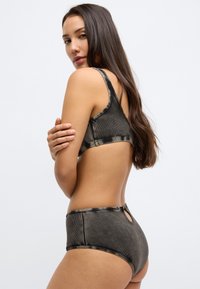 Σετ μπικίνι δύο τεμαχίων σε σκούρο καφέ χρώμα με υφασμάτινη υφή ραβδώσεων, ρυθμιζόμενους ιμάντες και λεπτομέρεια με άνοιγμα στο κάτω μέρος με ψηλή μέση.