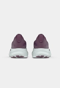 Vijolične atletske čevlje z mrežastim zgornjim delom z teksturo in belim gumijastim podplatom s strukturiranimi vzorci za oprijem. Zasnova iz zadnje strani prikazuje zanke na peti.
