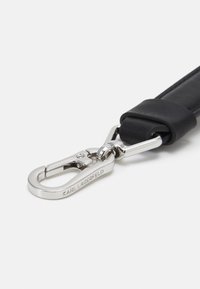 Svart läderrem med en silvermetallås. Låset är graverat med "KARL LAGERFELD". Remmen har en slät yta med minimal detaljer.