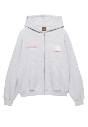 Grijze zip-up hoodie gemaakt van zachte stof. Voorzien van een capuchon, zakken aan de voorkant en bedrukte tekst in rood en wit. Losse pasvorm met geribbelde mouwen.