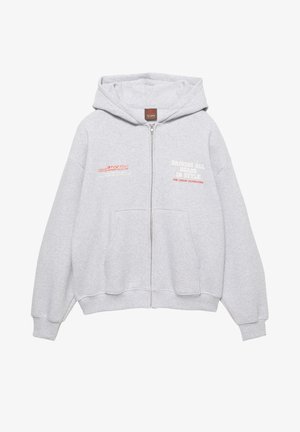 Gray zip-up hoodie made of soft fabric. Features a hood, front pockets, and printed text in red and white. Relaxed fit with ribbed cuffs.