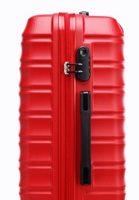 Red hard-shell suitcase with a textured surface, vertical ridges, a black zipper lock, and a side handle for easy transport.