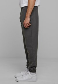 Grå bomuldsjoggers med slim fit og elastisk talje, der har sidelommer og elastiske manchetter, i kombination med hvide sneakers.