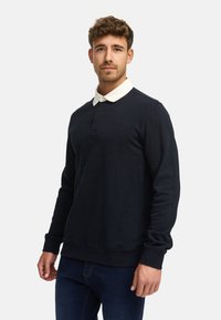 Marine sweatshirt med hvit polo-krage, lange ermer og ribbestrikkede mansjetter, med en subtil logo på brystet og en avslappet passform.