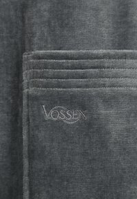 Gray cotton towel with a soft texture, featuring a woven design and embossed "VOSSEN" logo in a lighter gray thread on the corner.