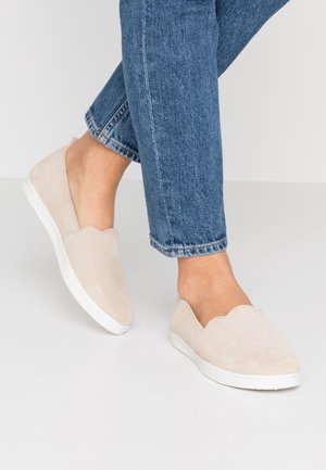 Jasnobeżowe buty wsuwane z falowanym wykończeniem, wykonane z zamszu, z białą gumową podeszwą i gładką fakturą.
