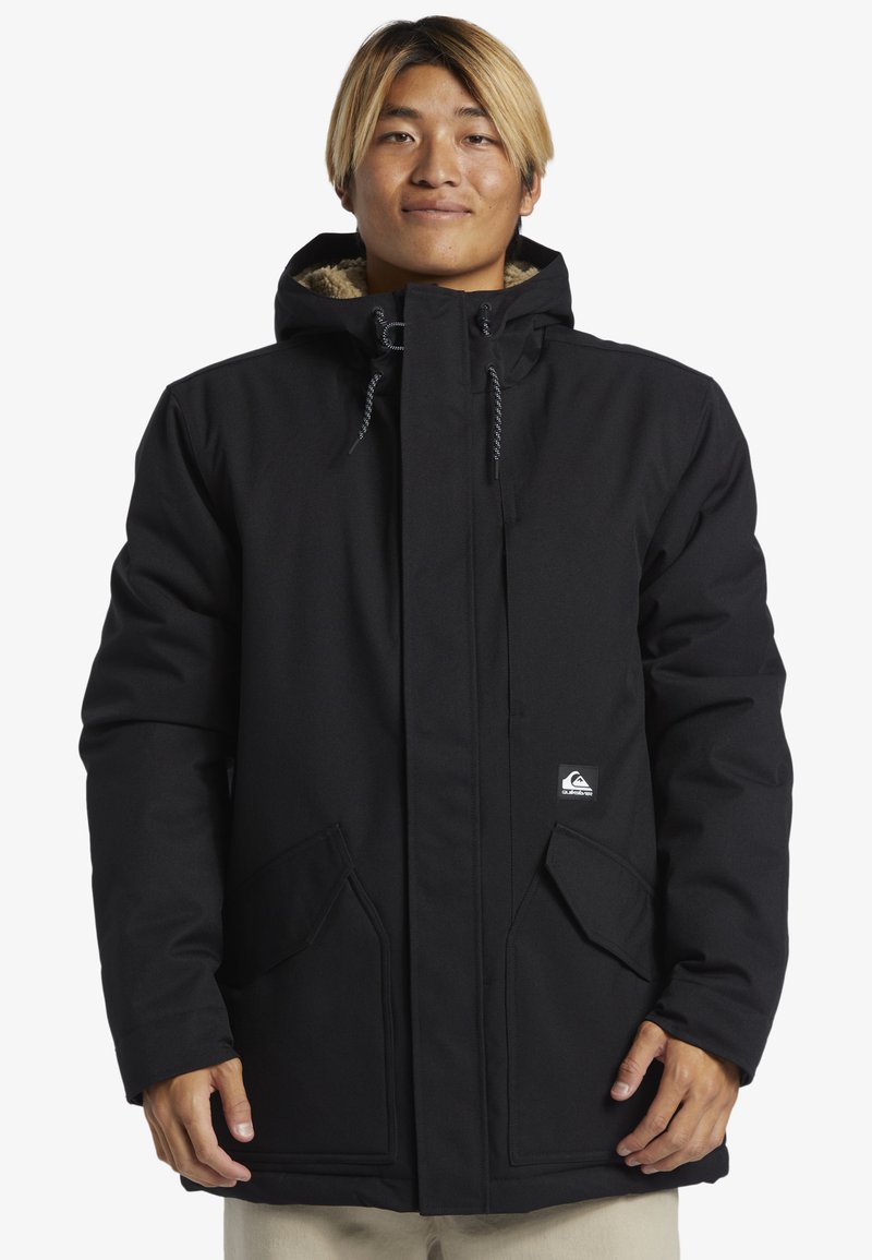 Sort isoleret parka med lynlås og knaplukning, store forlommer, snorjusterbar hætte og blødt foer. Har logo patch foran.
