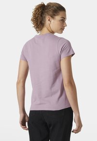 Camiseta de manga corta color lavanda con cuello redondo, hecha de algodón suave, que presenta una textura suave y un corte casual. Se muestra la vista posterior.